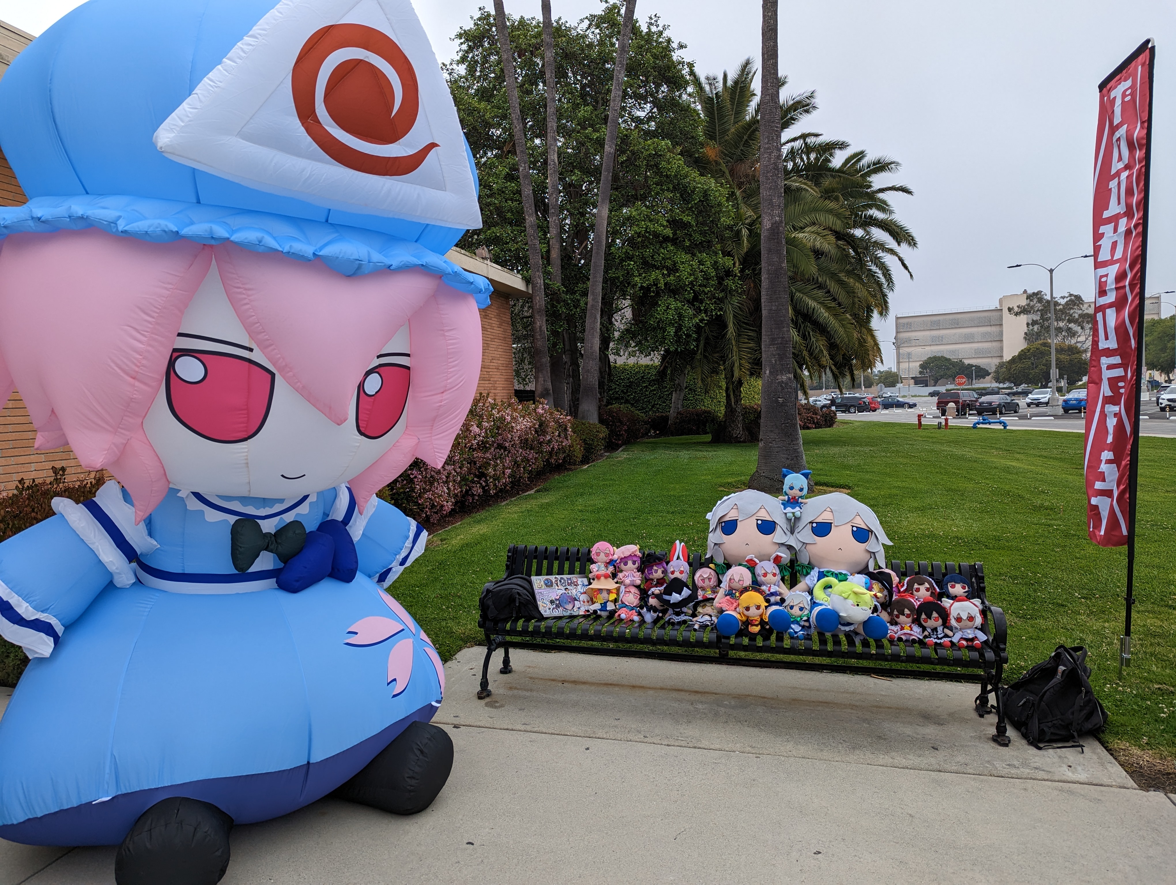 bench filled with fumos next to large inflated Yuyuko fumo